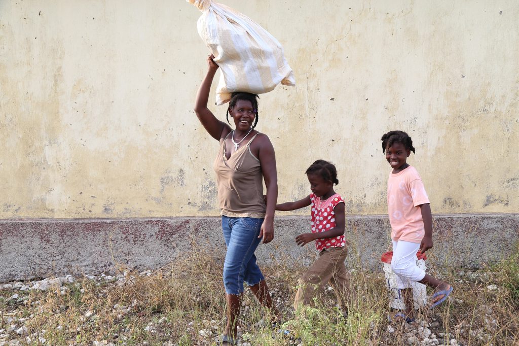 Gerda Milien, 36, walks home after a CRS distribution of food, blankets, hygiene kits, cooking pots and tarps and ropes in Roche Bateau. Gerda who has five children lost her home when Hurricane Matthew hit the town of Roche a Bateau. Roche a Bateau, a town roughly 30 miles south of Les Anglaise where the eye of Hurricane Matthew struck, has very few homes standing. 

Photo by Marie Arago for Catholic Relief Services