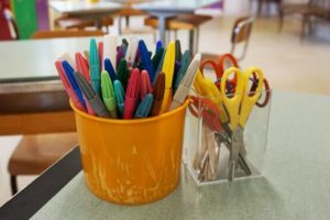 Contenitori con colori e forbici in un'aula scolastica.